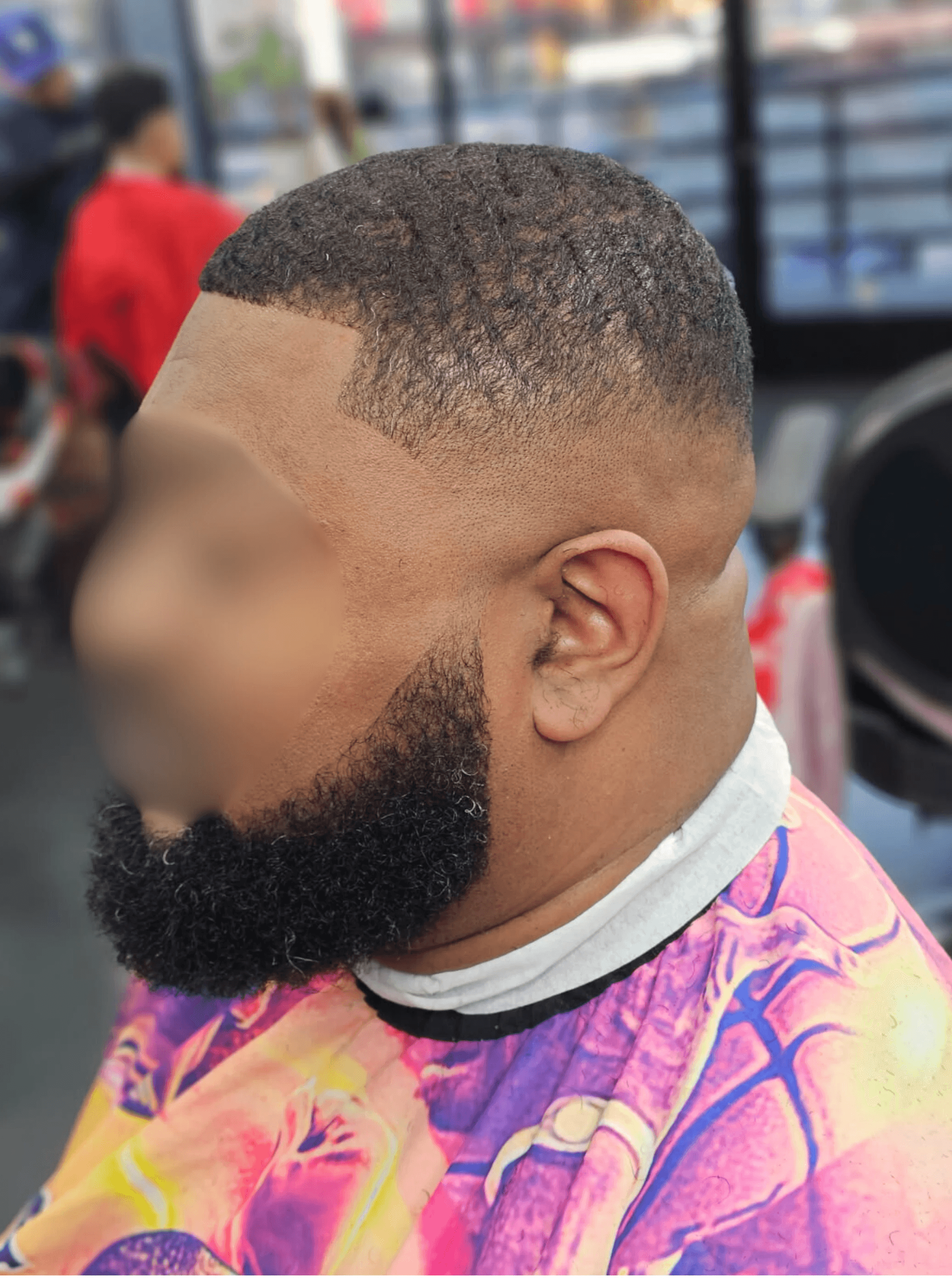 Man with short buzz cut and waves, low fade taper, and full edged beard.