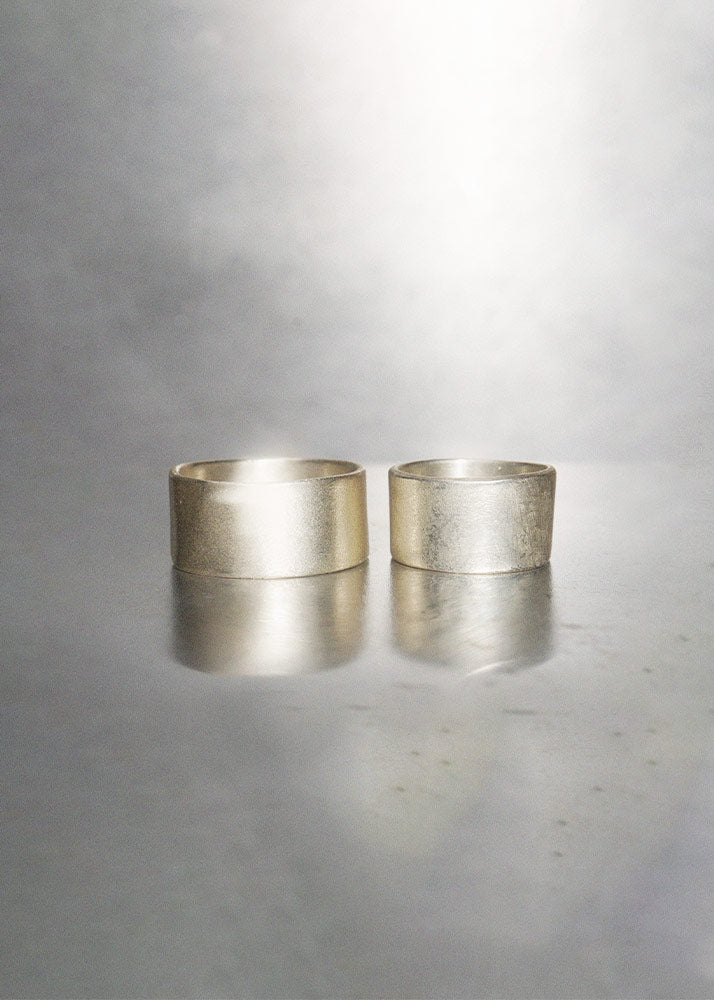 Two silver rings on a reflective gray surface with a gray background