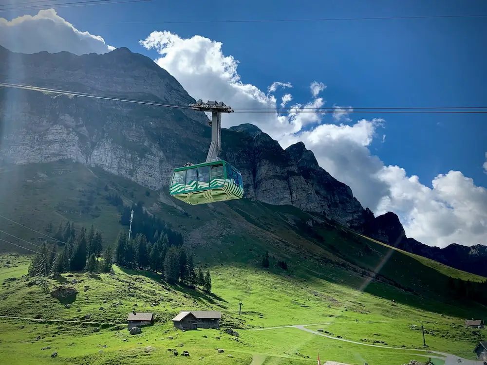 Säntis Seilbahn an schönem Sommertag mit Bergen und grüner Wiese im Hintergrund