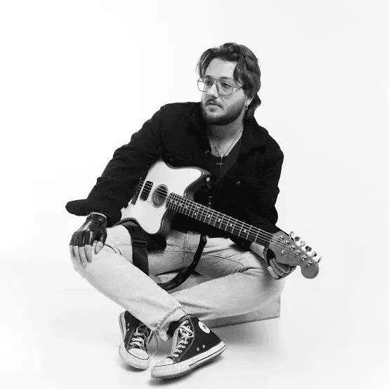 A man with long hair is working on a computer.