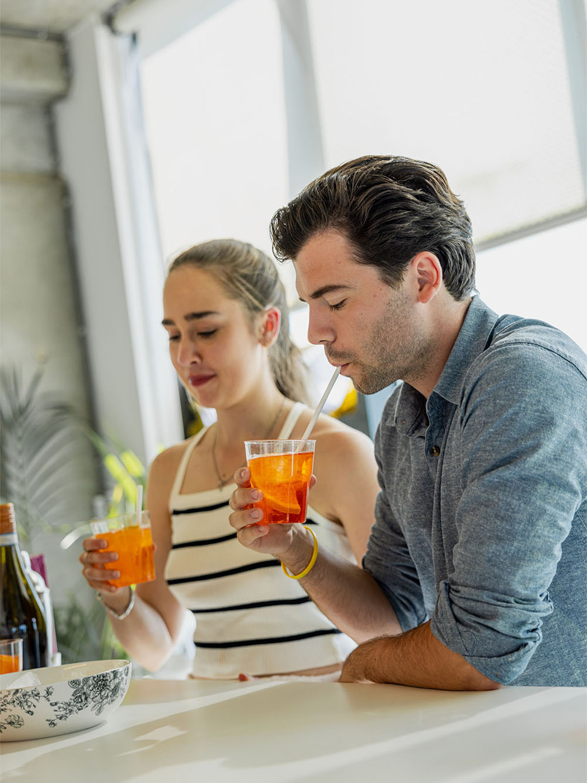 Two people drinking drinks in a well-lit room