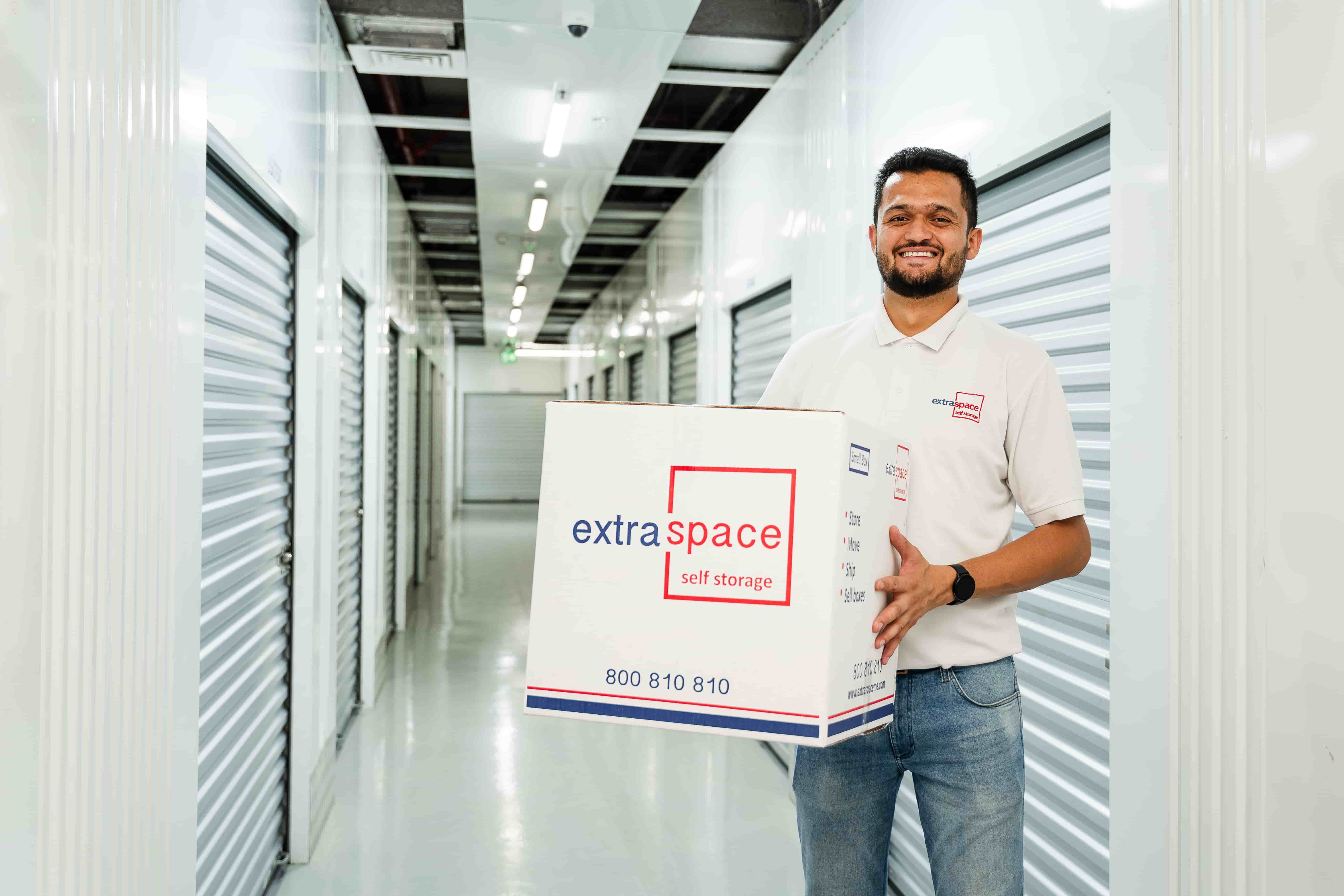Extra Space professional carrying a storage box while supporting an international relocation. 