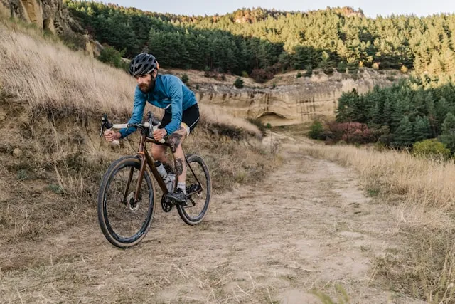 Cyclist riding on a dirt trail through dry hills during an outdoor session