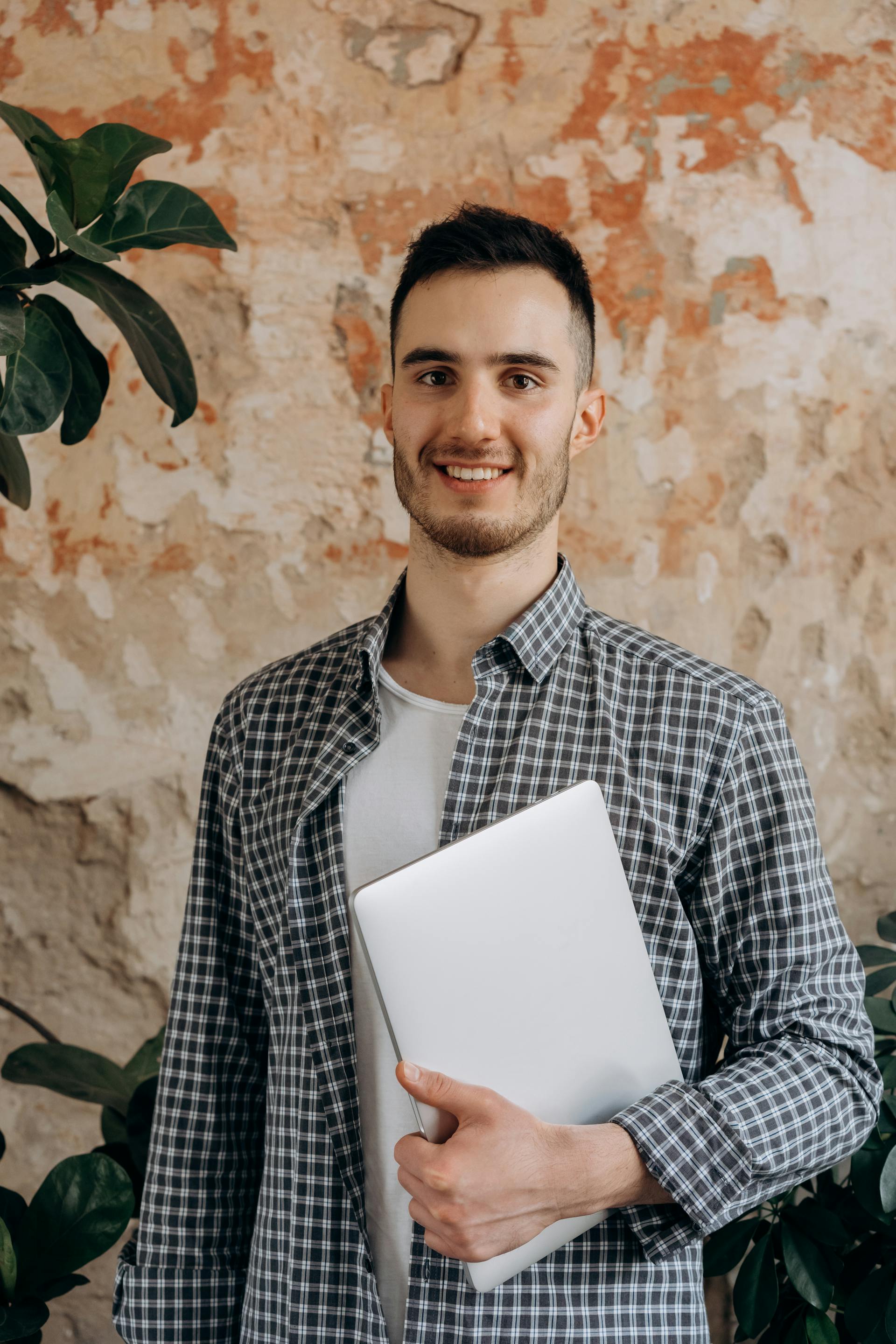 A Man Wearing A Man Wearing Checkered Long Sleeves While Holding a Laptop