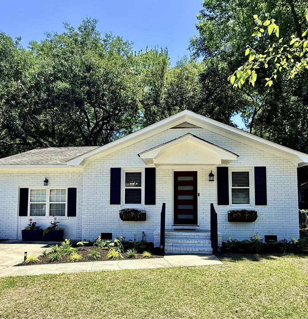 White brick ranch house with black shutters and window boxes under live oaks in Mount Pleasant