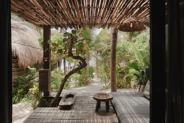 Standard Room at Nômade Tulum, with bed, pillows, and jungle view through large windows.