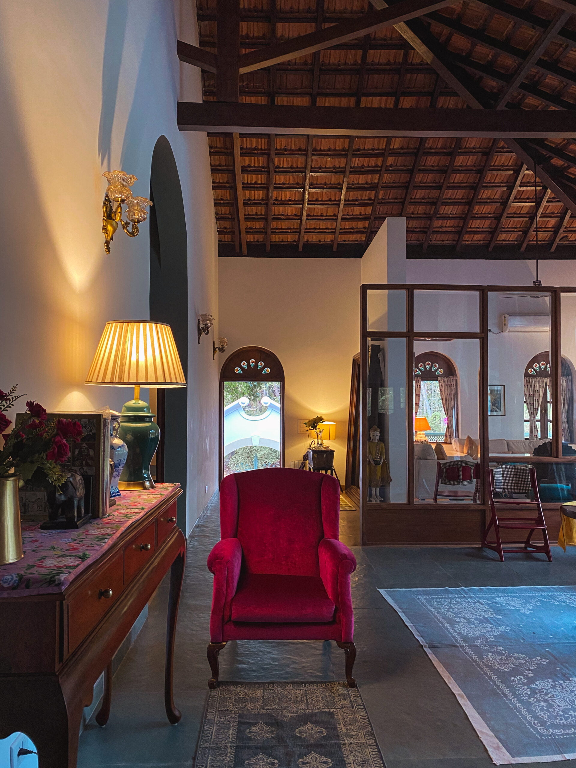 The open-plan living area is defined by soaring exposed wooden trusses and a wood-framed glass partition, bathed in warm ambient light.