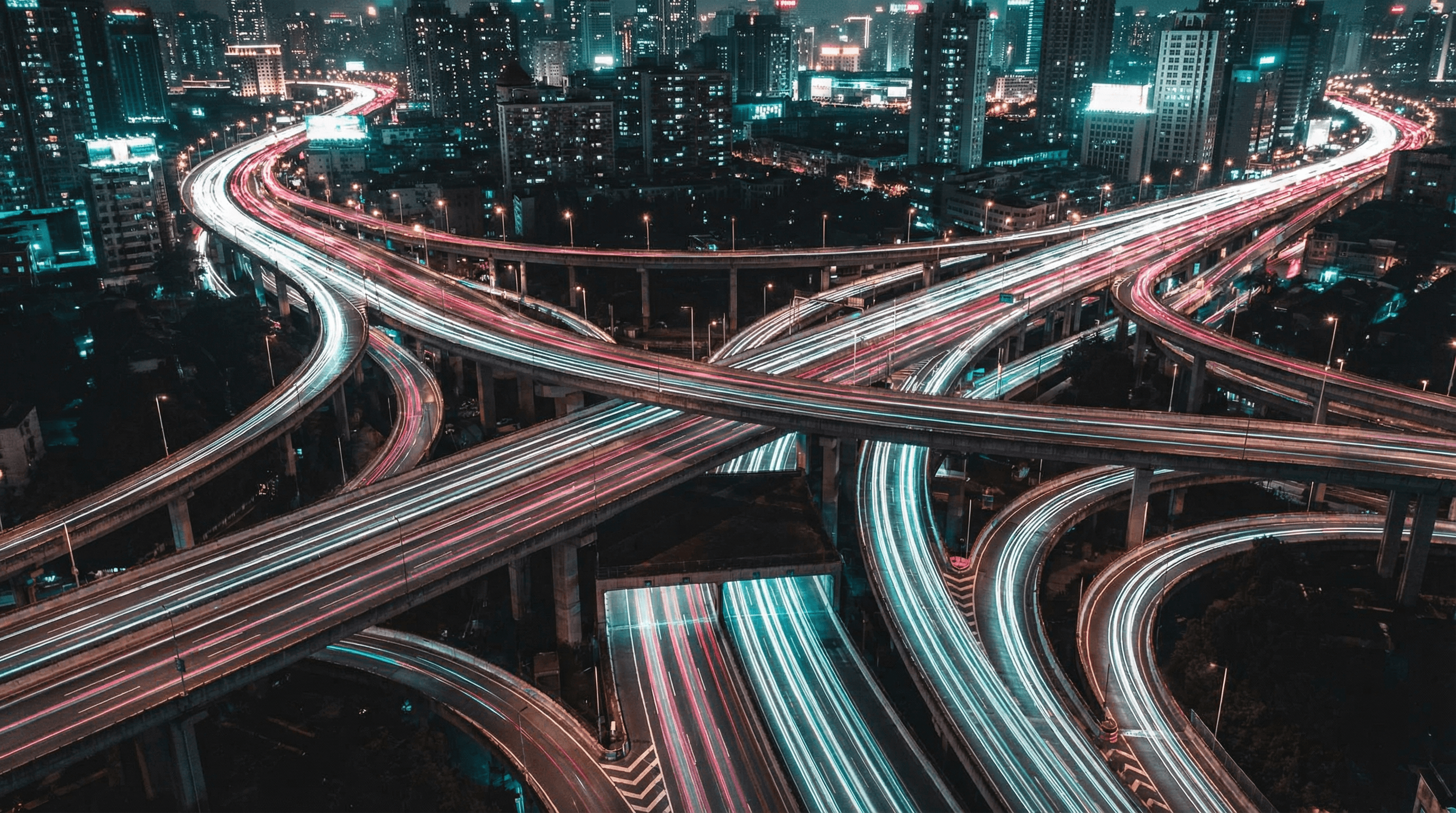 A man and woman sit on beige chairs in a modern room with a red paneled wall. A red pendant light hangs above a wooden coffee table between them.