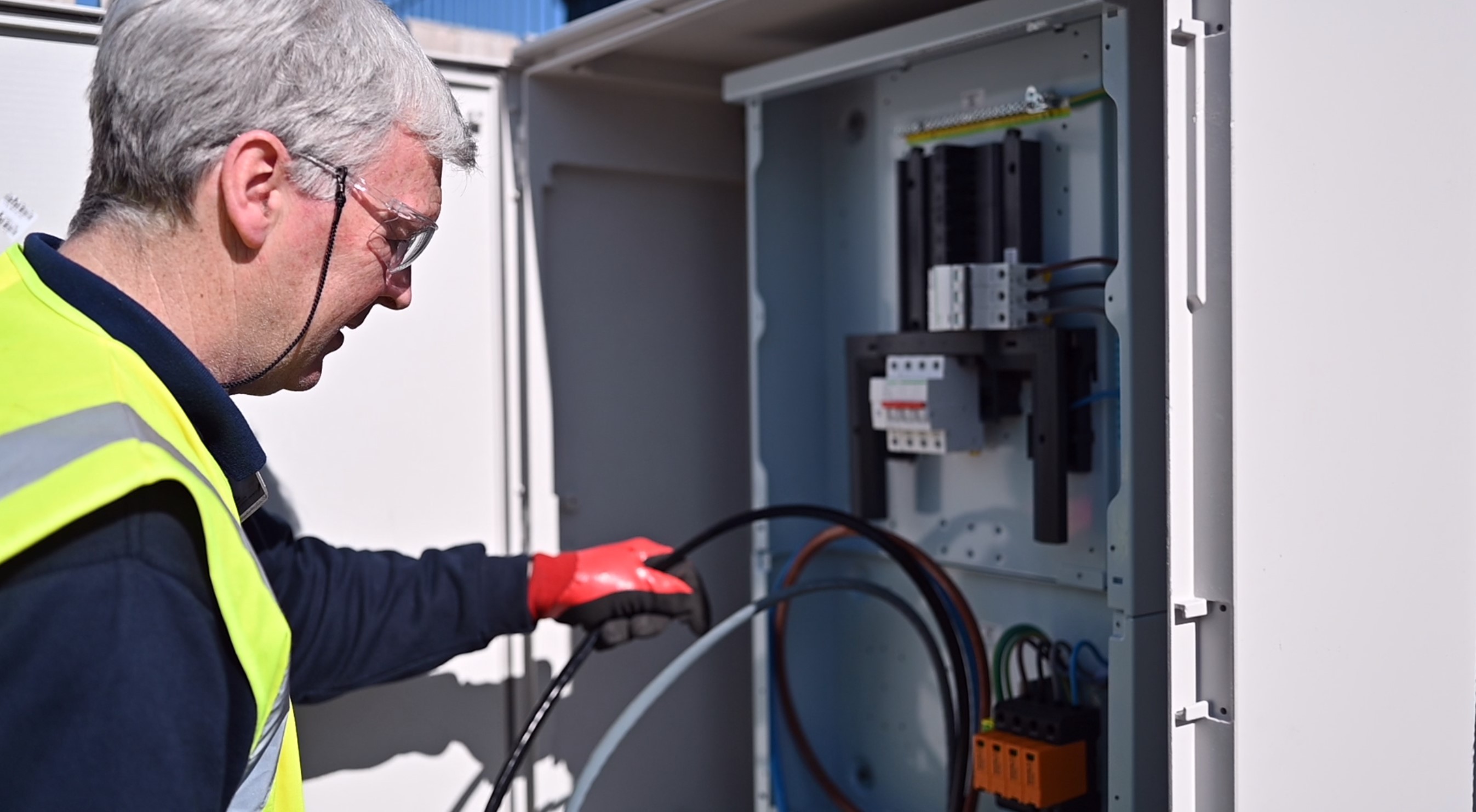 CASC electrical engineer testing wiring inside an outdoor distribution cabinet.
