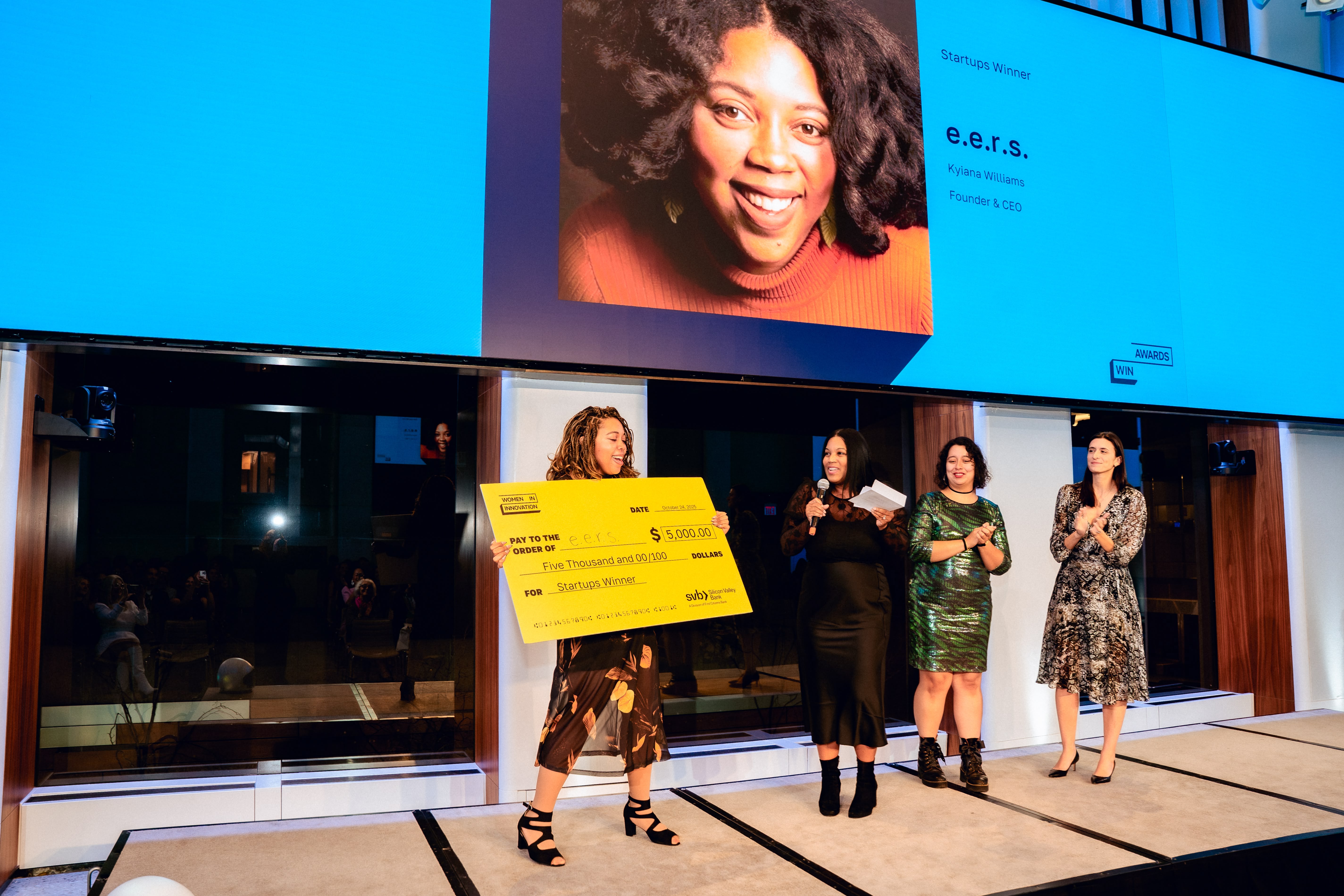 Start-up winner Kiyana Williams holding up a large yellow check