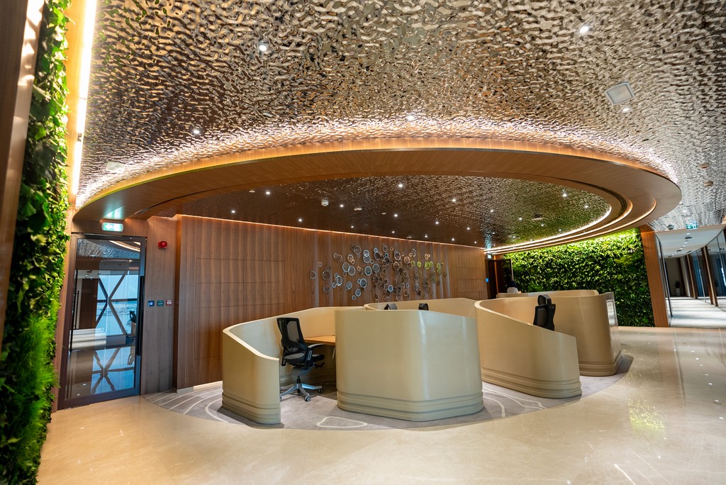 Modern reception area at Office Square, Al Fattan Tower in Dubai Marina, featuring a sleek marble desk, curved wood accents, and ambient lighting.