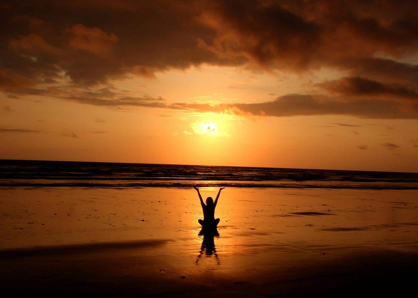 Benefits of yoga - Woman stretching on a beach at sunset