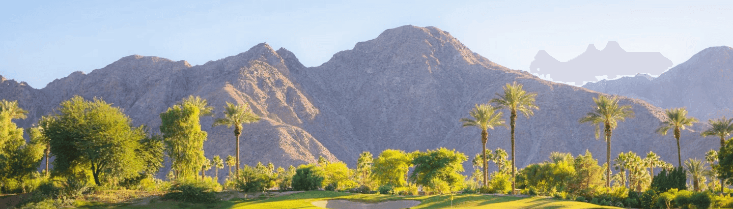 Two people sit at a dark wooden table, smiling warmly at the camera. They have laptops open, creating a friendly and collaborative atmosphere.