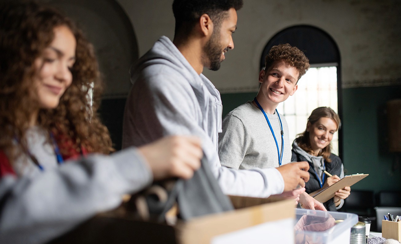 Group of young people with clipboard sorting through donations