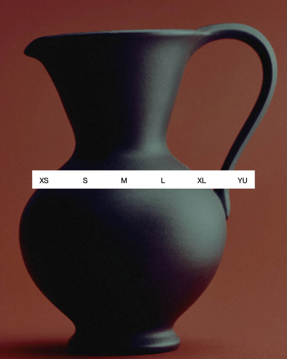 A photo of a vase with a white label with sizes against a red background.