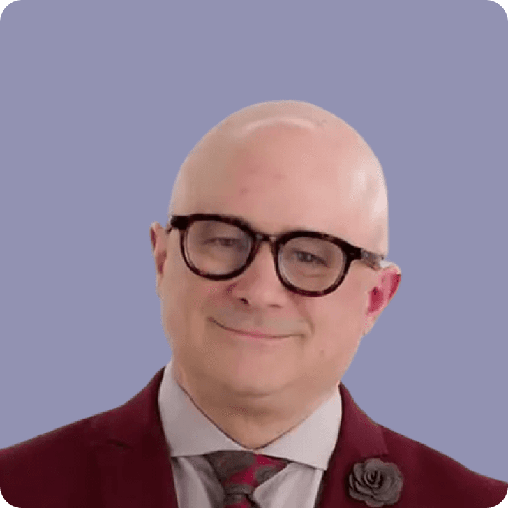 A bald man with glasses in a redish suit in front of a purple background