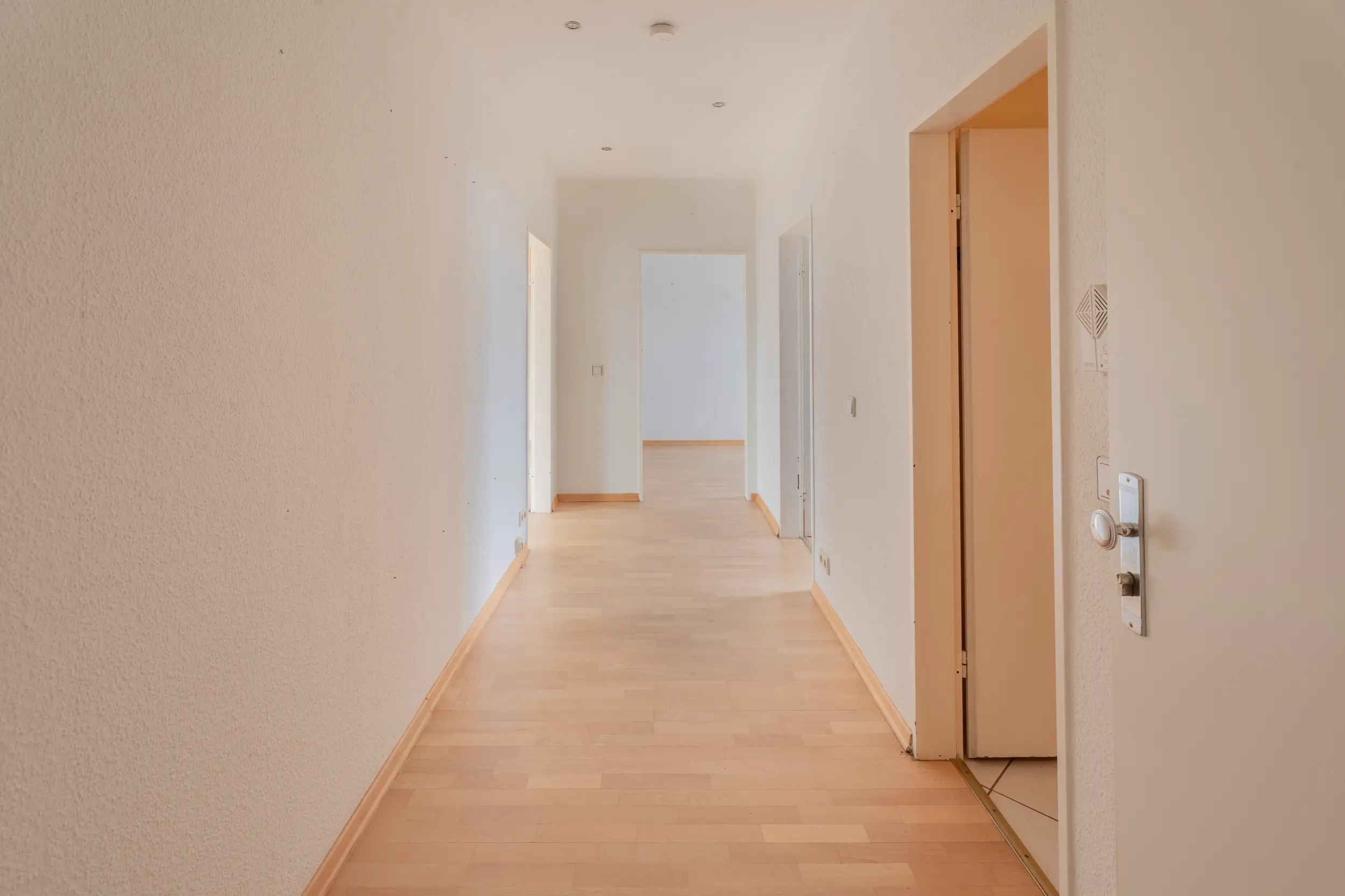 Heller Flur der Dachgeschosswohnung mit Laminatboden, weißen Wänden und Zugang zu den einzelnen Wohnräumen.