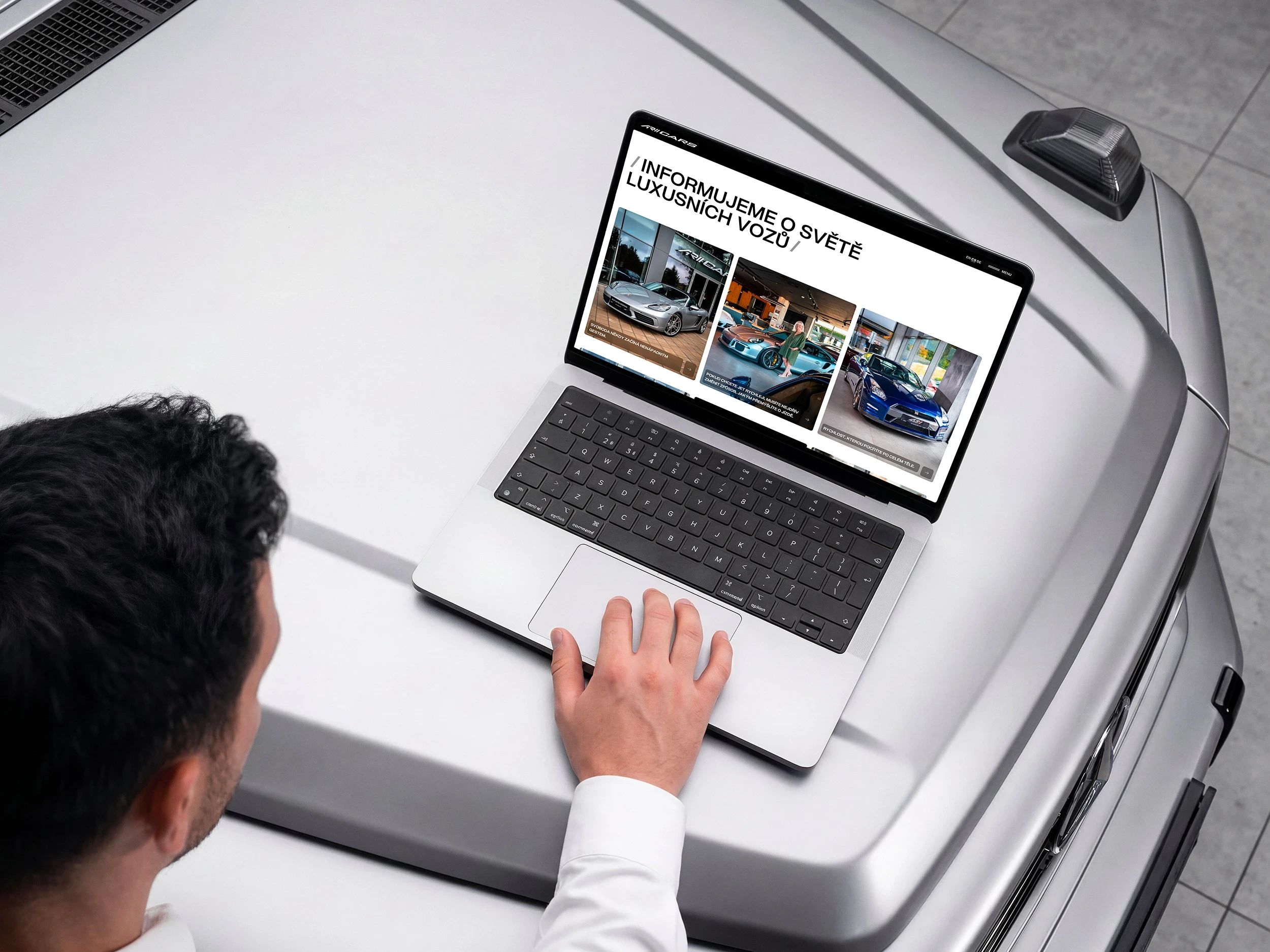 Groovio a AR CARS mockup webové stránky na míru, které ukazuje muž v shorwoomu na kapotě Mercedesu G Class