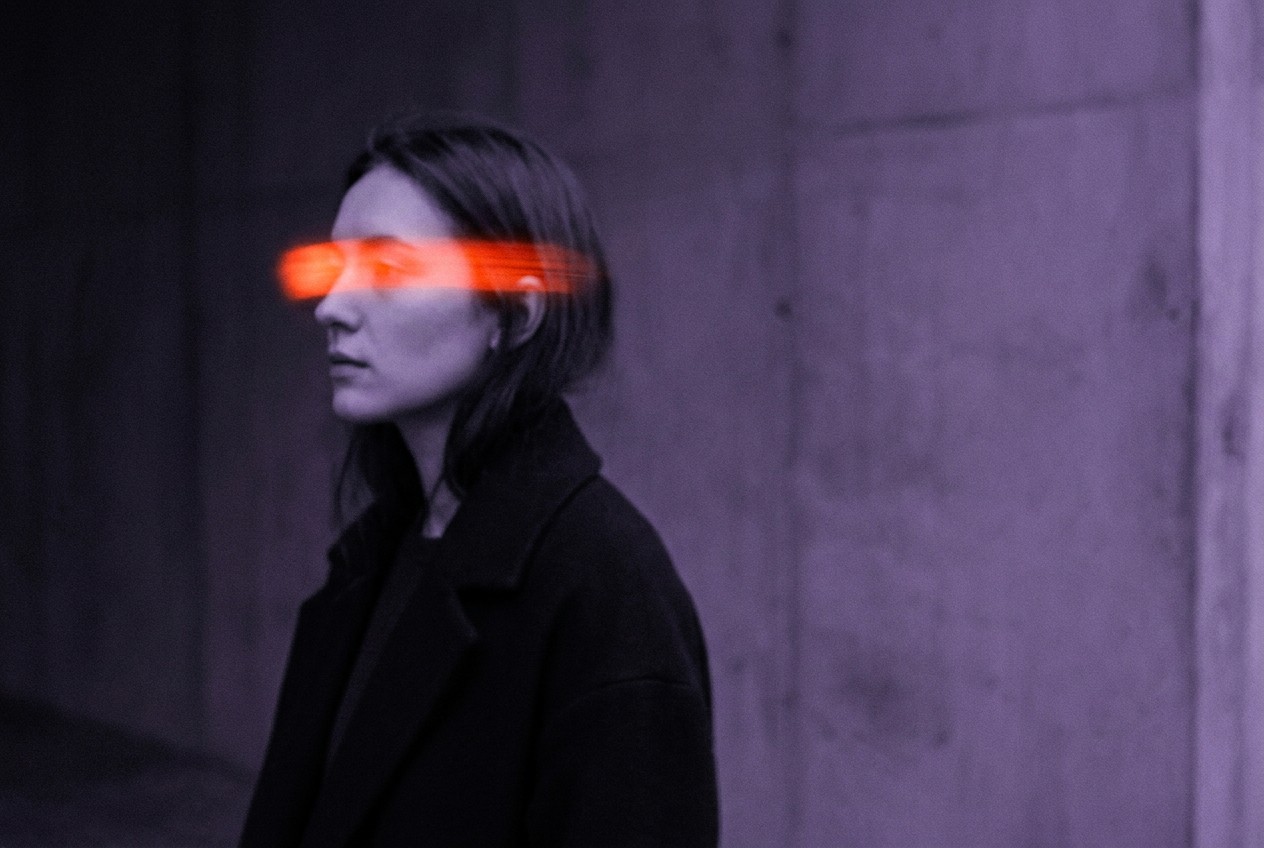 Side profile of a woman in violet light with a glowing orange band across her eyes