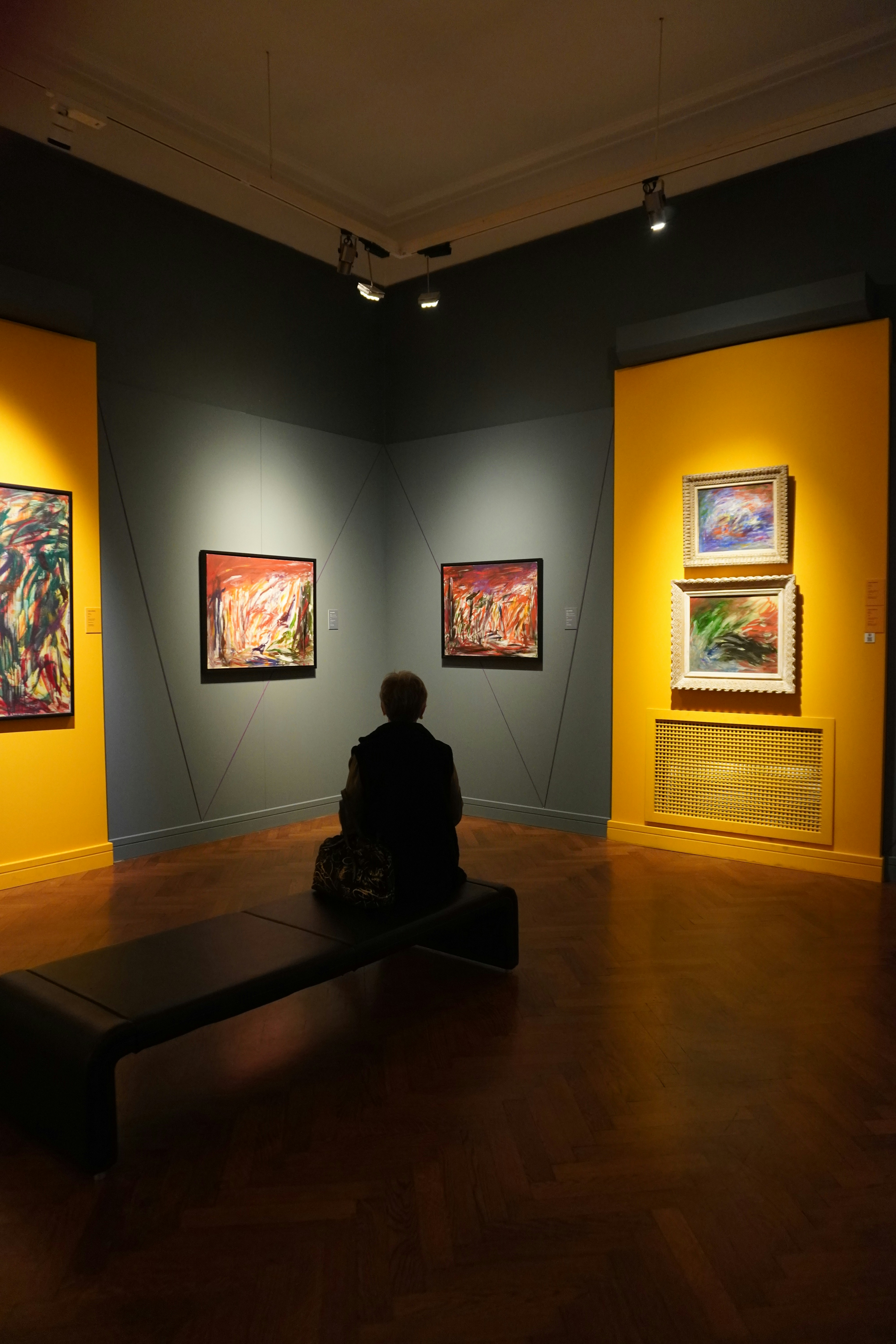 Person sits on bench in art gallery viewing paintings