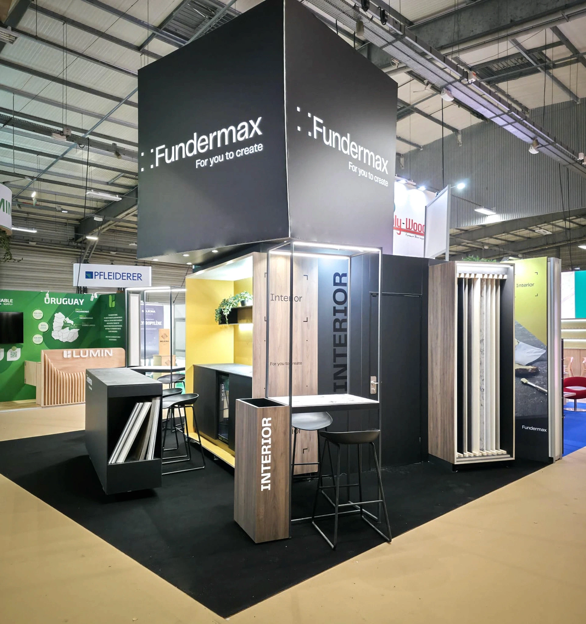 Stand Fundermax panneaux HPL et stratifiés compacts conçu par EXPACE au Carrefour International du Bois (CIB) 2026 — cube noir suspendu, pôles Interior et Exterior et tours d'échantillons de décors