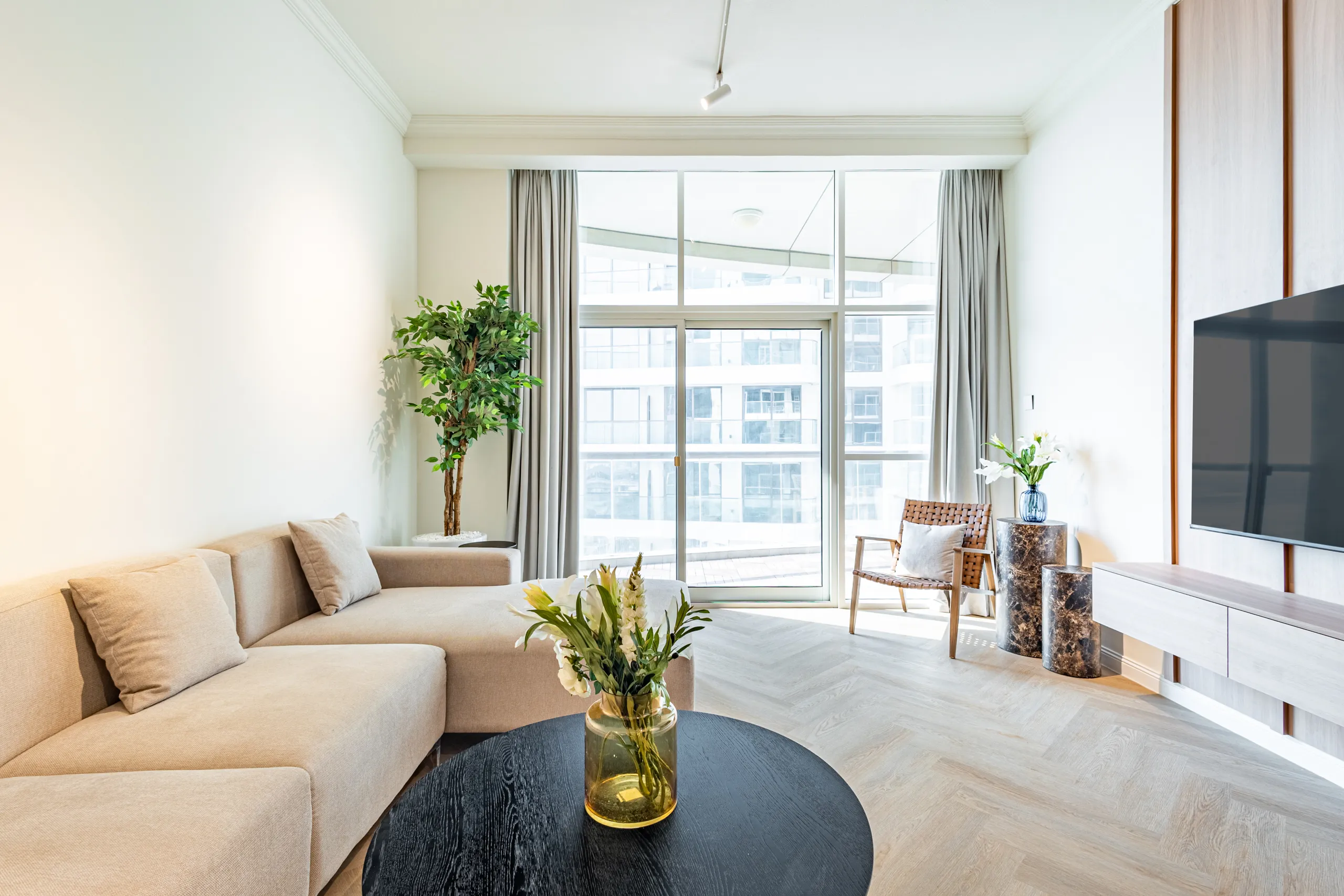 Living room with a big window, cozy couch and a tv.