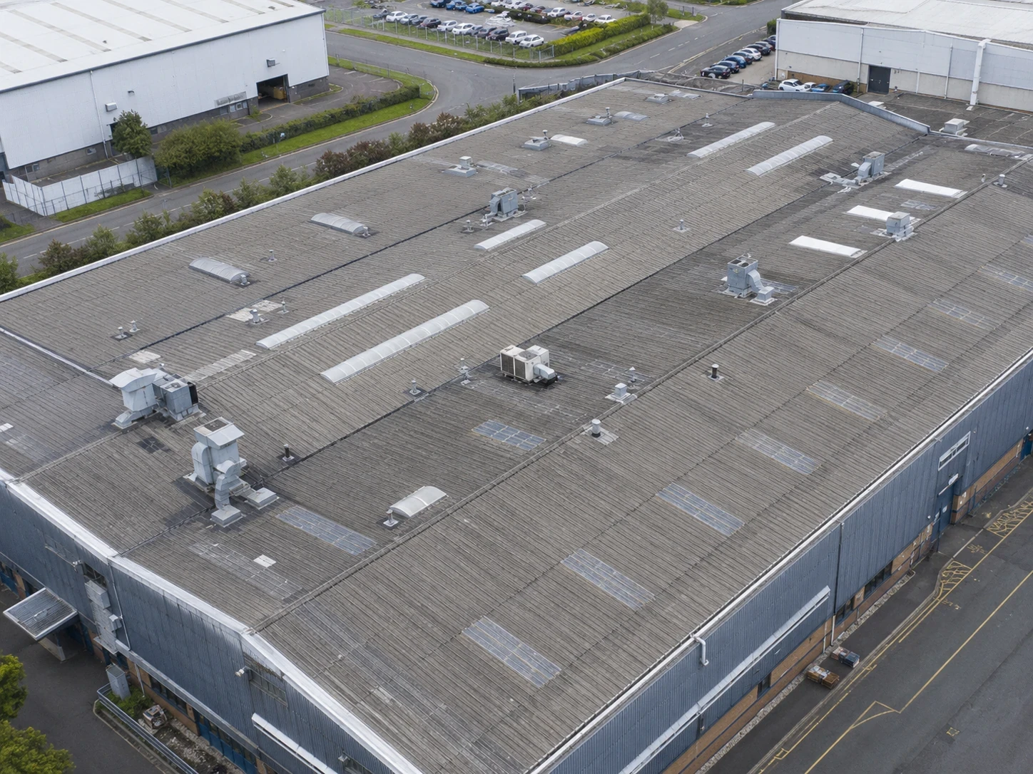 Aerial drone view of a large UK commercial roof showing gutters and rooflights