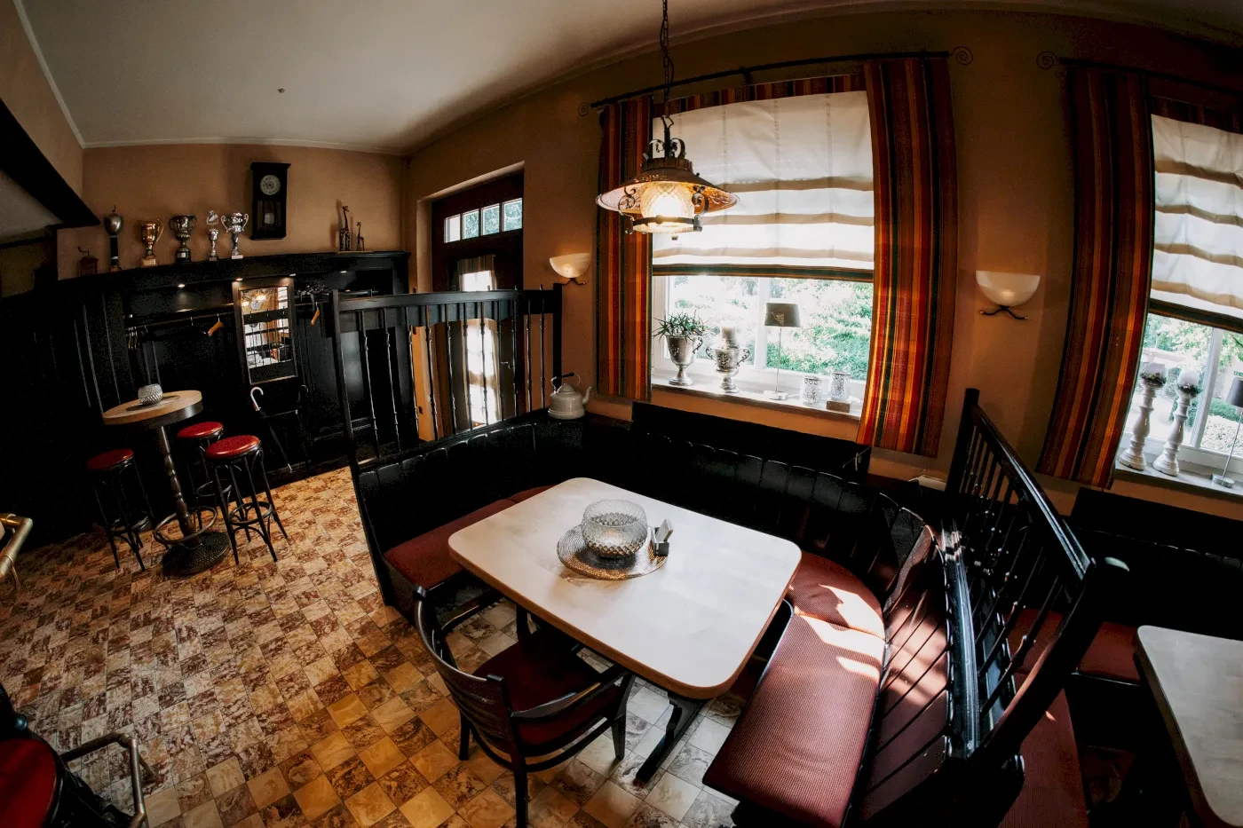 Gemütliches Restaurant mit runden Tischen, roten Stühlen und einem Fenster mit Tageslicht. 