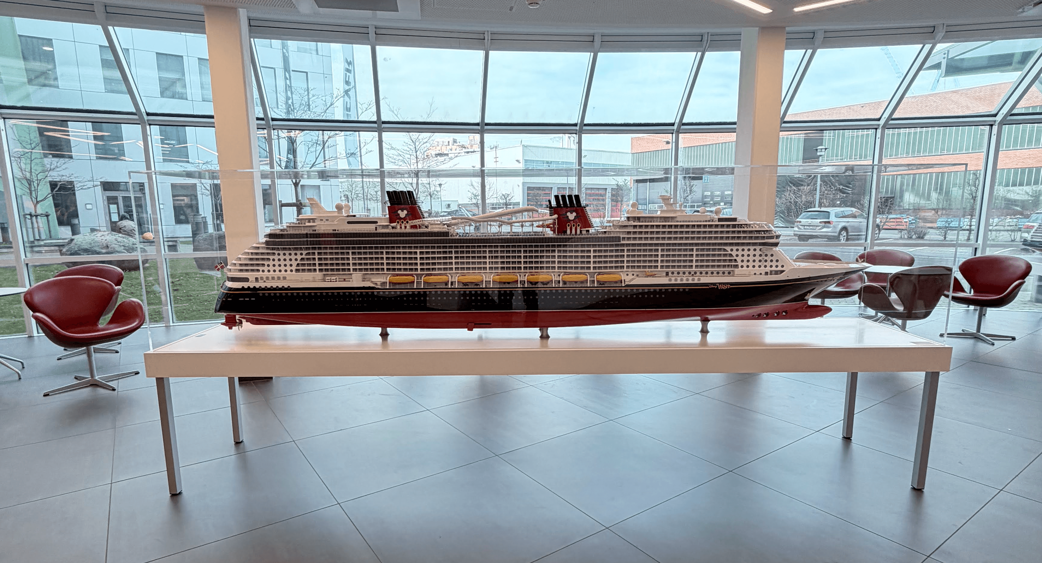 A person wearing a virtual reality headset stands in front of multiple screens, engaged in a digital experience.