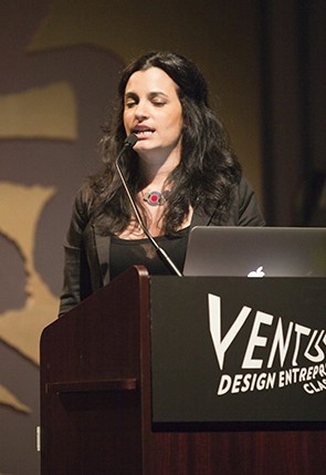 a portrait of a woman dressed in black on a stand is giving a speech