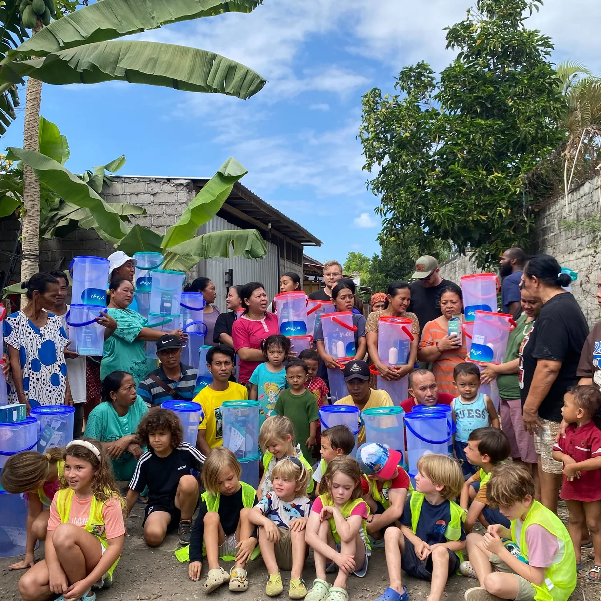 Community members and children holding water filter buckets