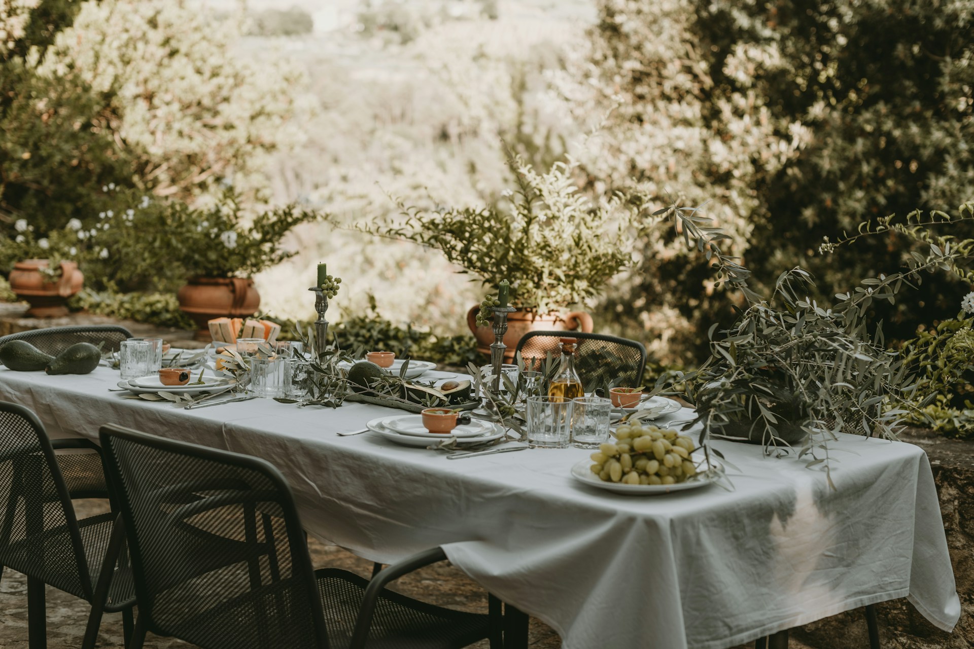 A serene outdoor wedding setup with white chairs arranged on green grass under a canopy of trees.