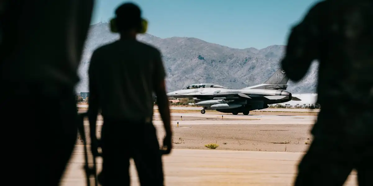 Ground crew watching an F-16 fighter jet on the runway — Semantic defense