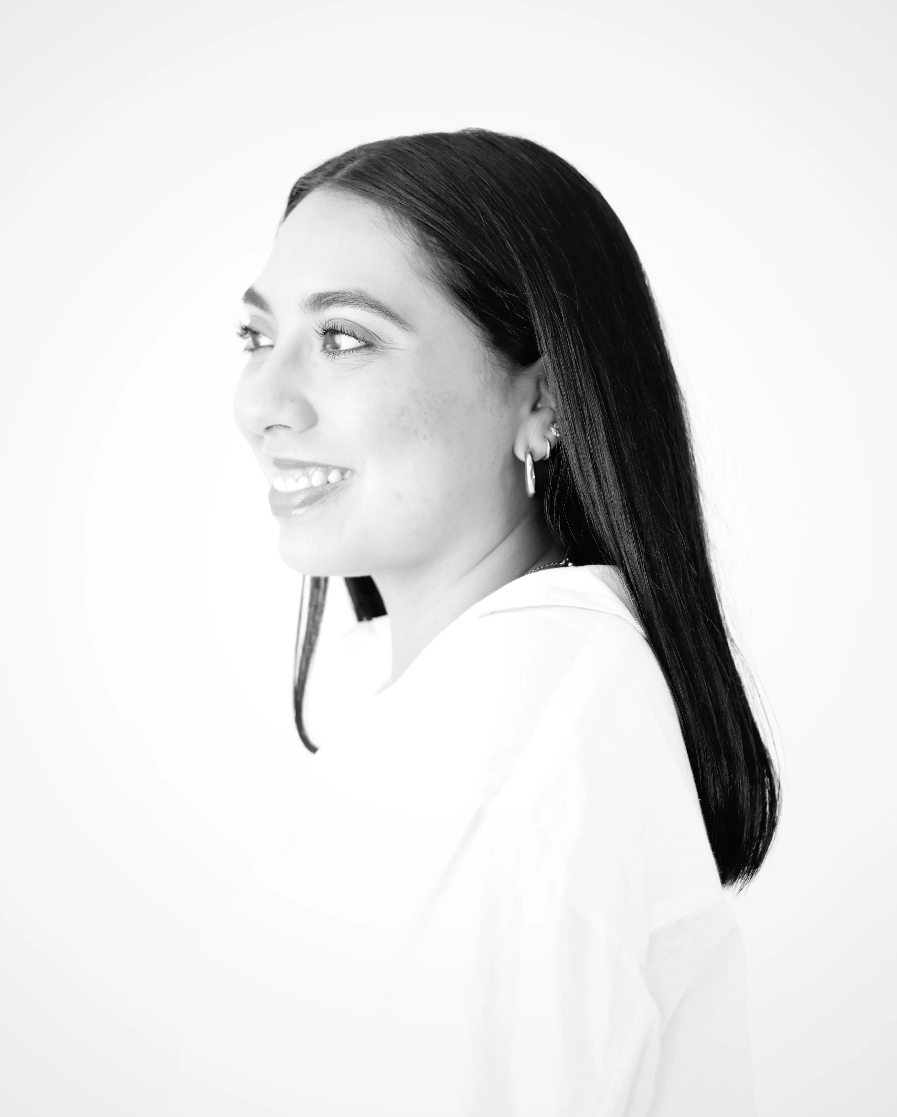 Retrato profesional de mujer mirando hacia la derecha con fondo blanco.