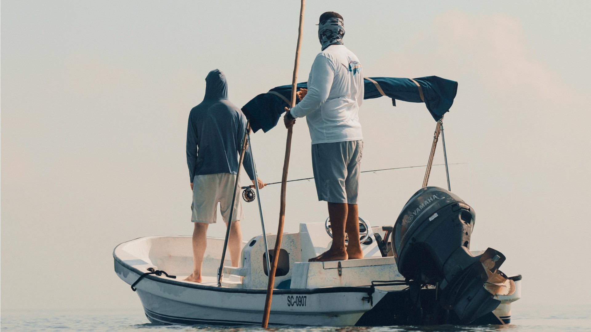 Fly fishing angler and fly fishing guide Marlon Leslie on his skiff, looking over a Belizian flat