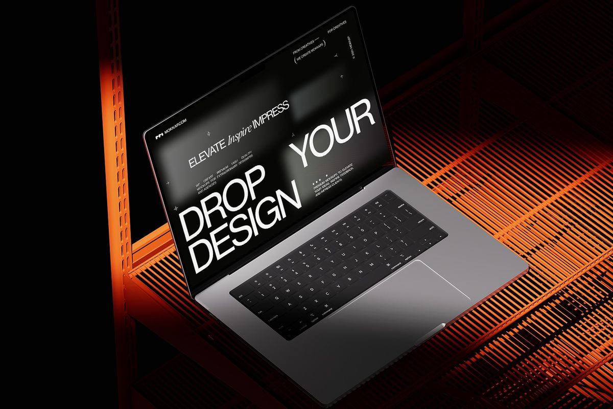 A laptop displaying "DROP DESIGN" text on a dark, orange-lit surface.
