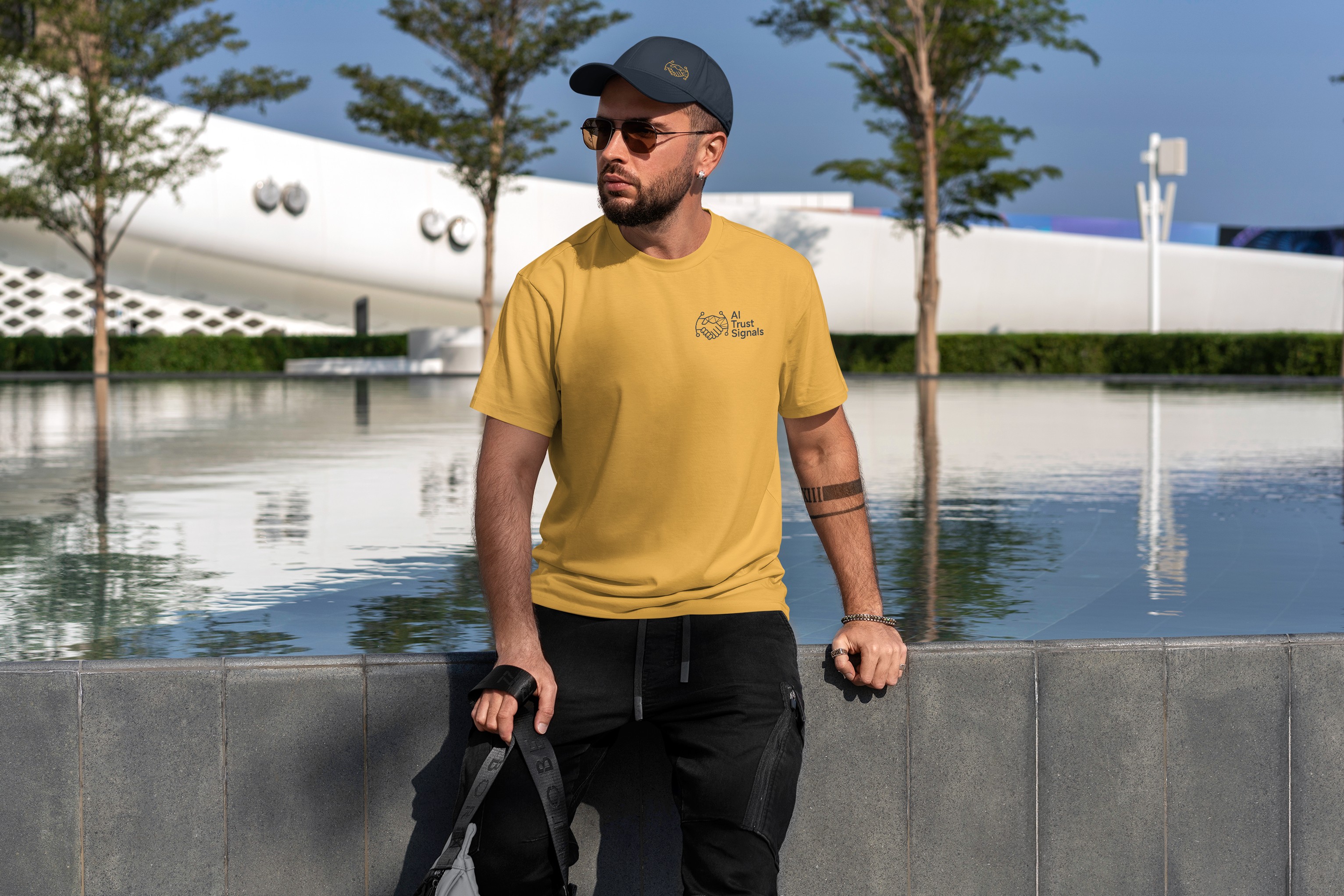 Man wearing AI Trust Signals logo T-shirt and cap, looking towards a laptop displaying the AI Trust Signals logo on its screen, set against a modern outdoor backdrop.