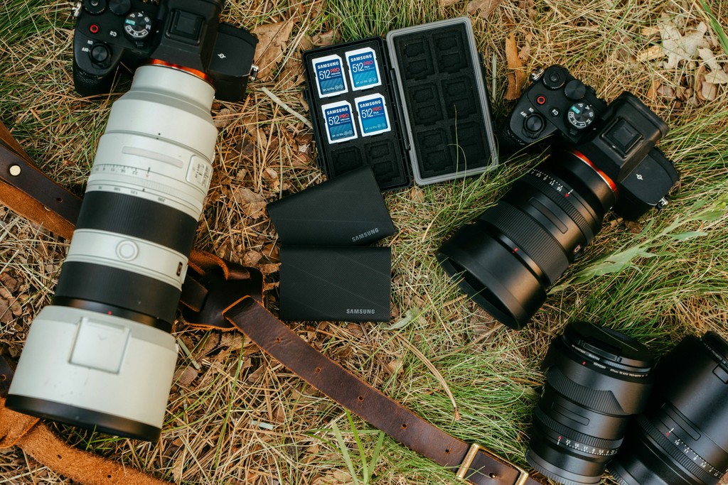 Two cameras with lenses and accessories on grass
