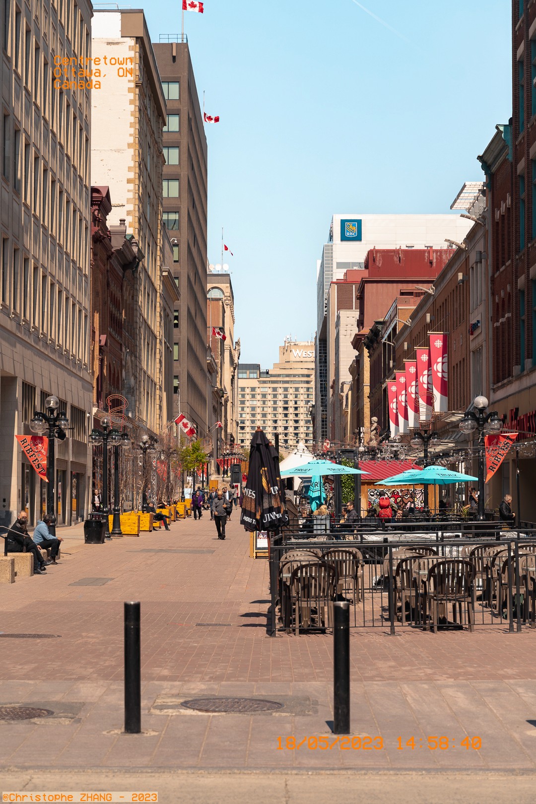 Rue piétonne du centre-ville d'Ottawa avec terrasses et drapeaux canadiens