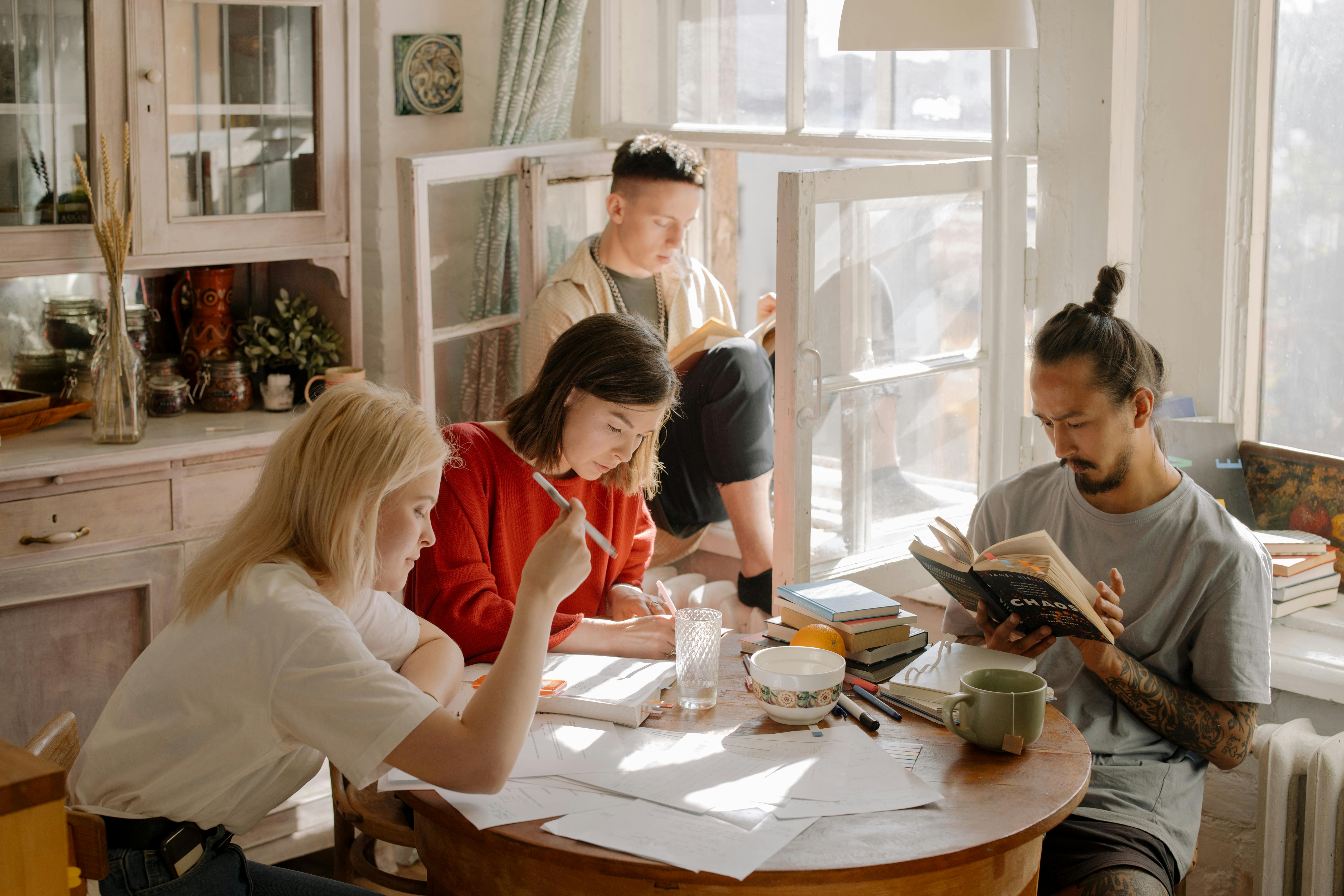 Woman in White Long Sleeve Shirt Sitting Beside Woman in Red Shirt during a study group session
