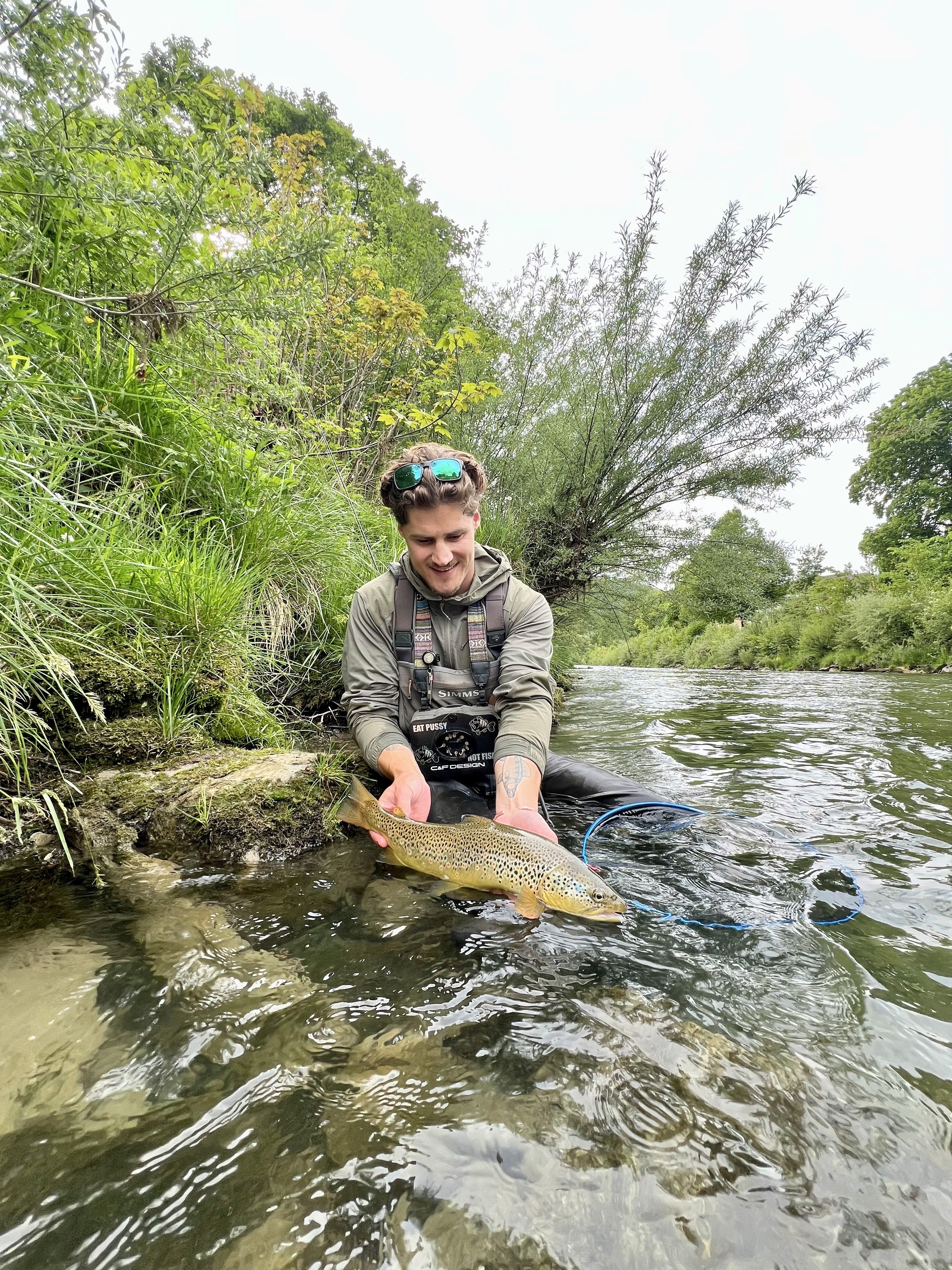 Fabio holding a brown trout beside a river
