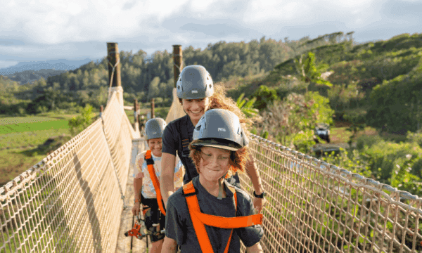 Family of zipliners walks across a suspension bridge at CLIMB Works.