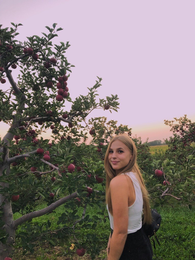 Sabrina standing in front of orchard