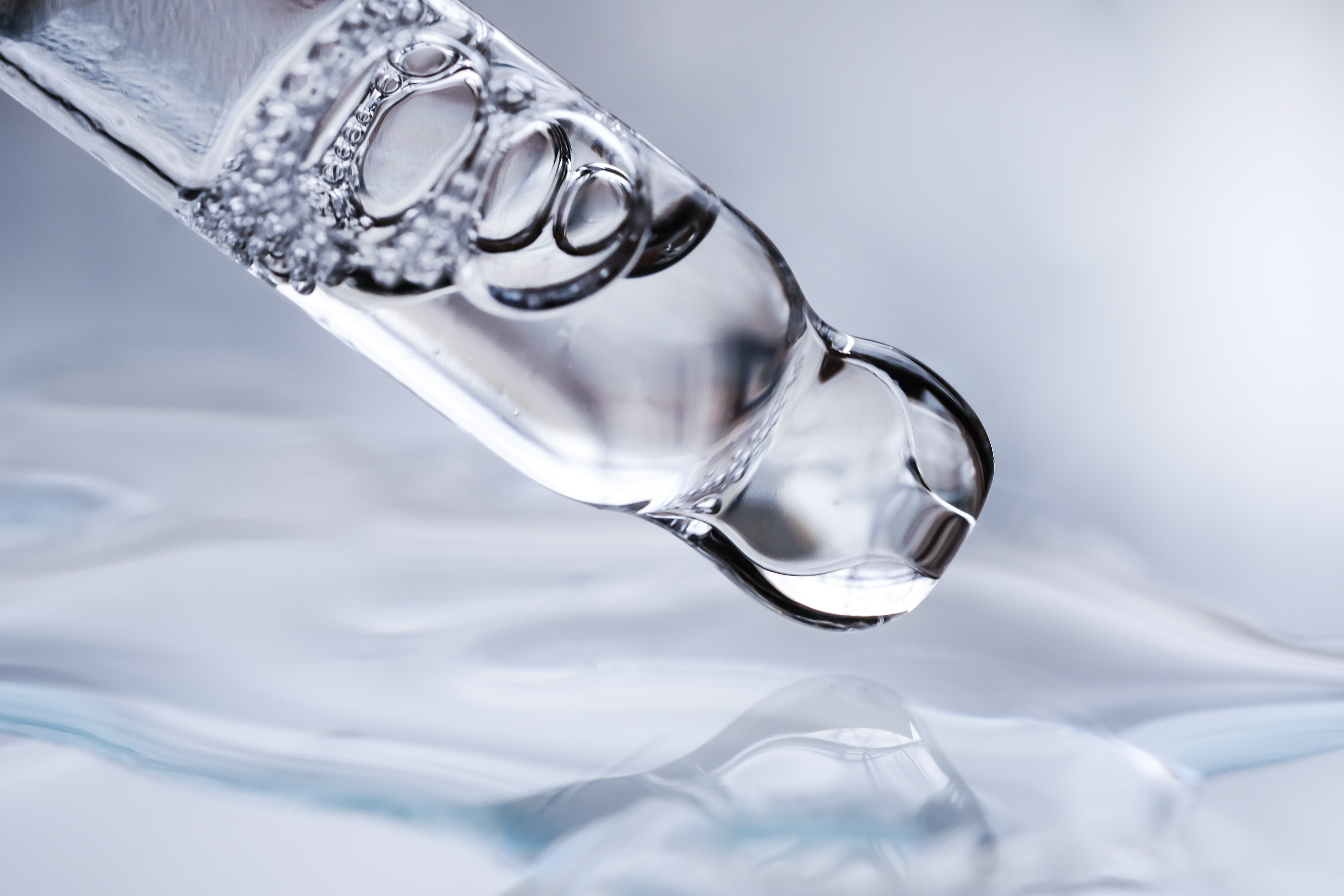 Dropper with liquid and bubbles over water.
