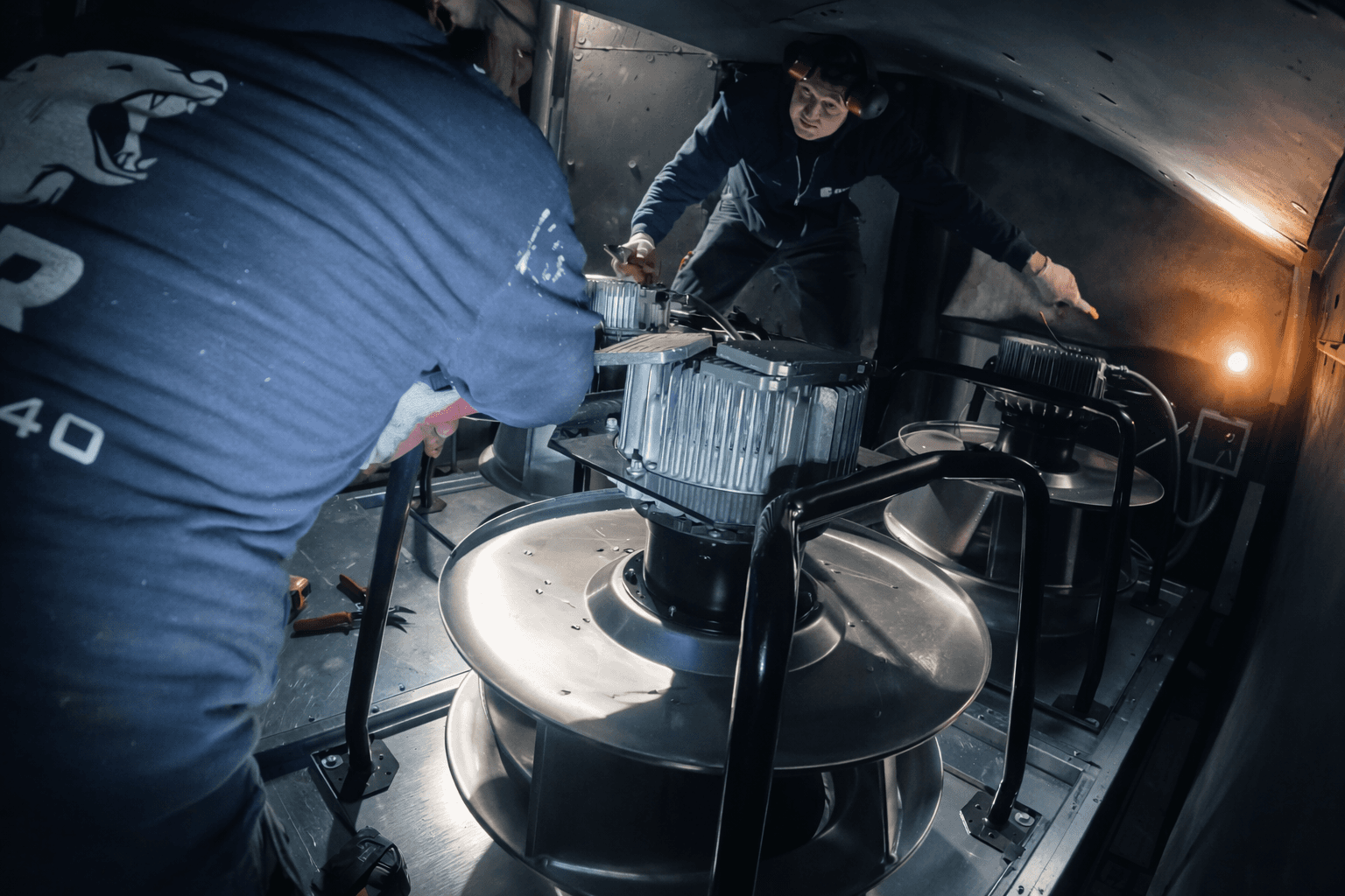 GRR technicians replacing a large HVAC fan assembly inside a tight-access mechanical unit in New York City