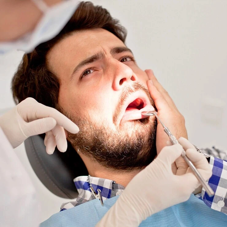 Dentist examining a male patient's teeth and mouth up close.