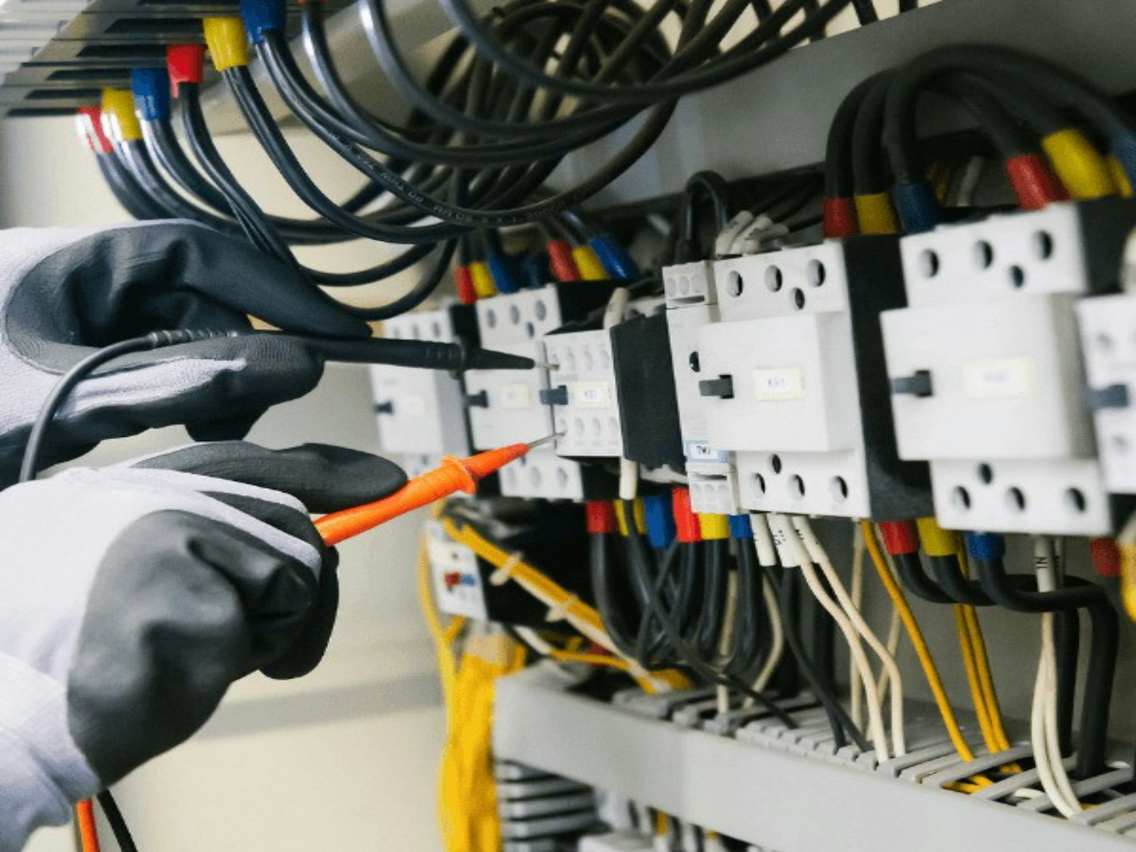 Electrician testing an electrical circuit with a professional meter and insulated leads