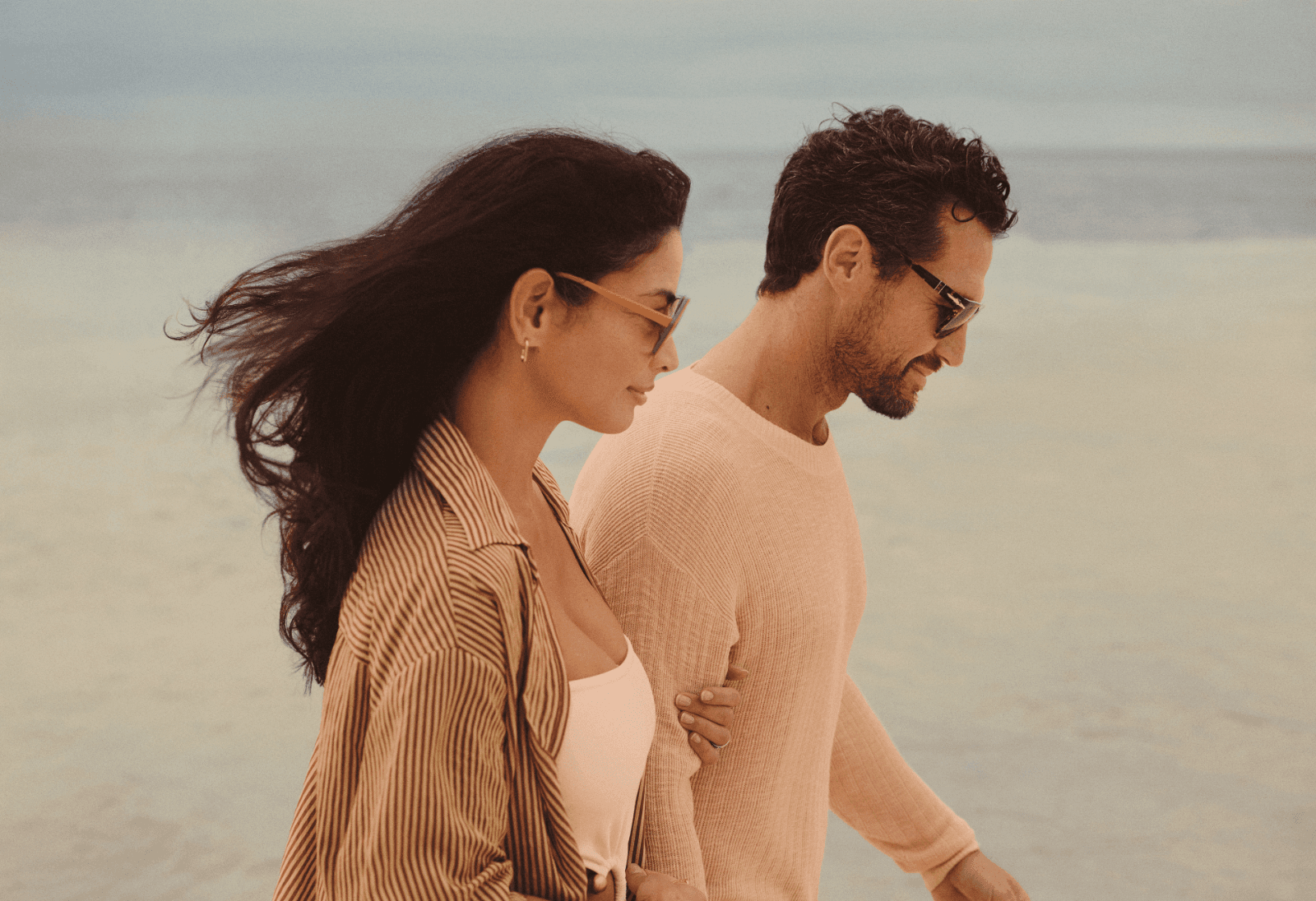 Couple in sunglasses walking arm in arm by the sea, Ritz-Carlton Yacht Collection commercial still by Inquire