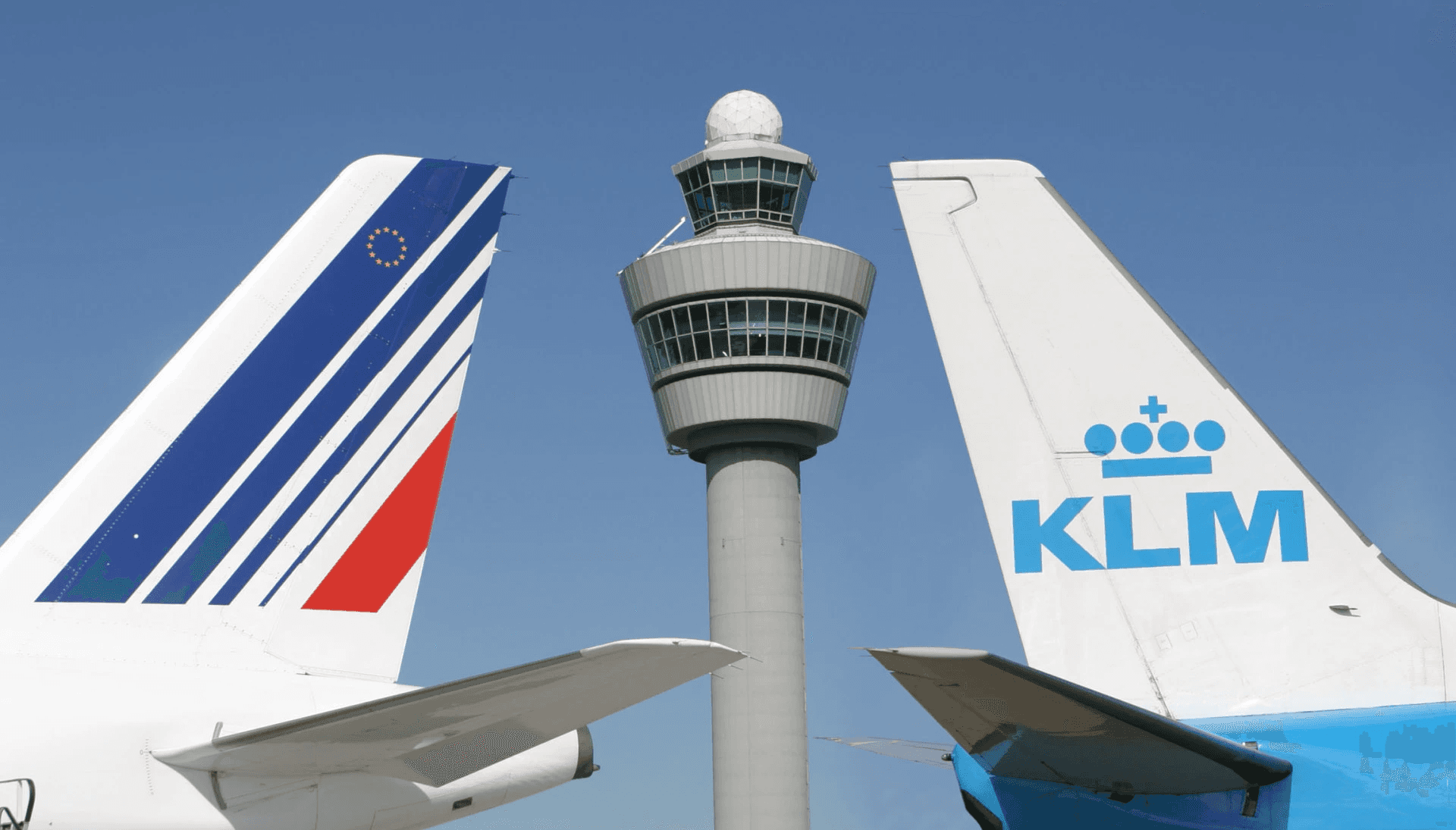 the tails of a KLM and Air France aircraft together with the control tower between them