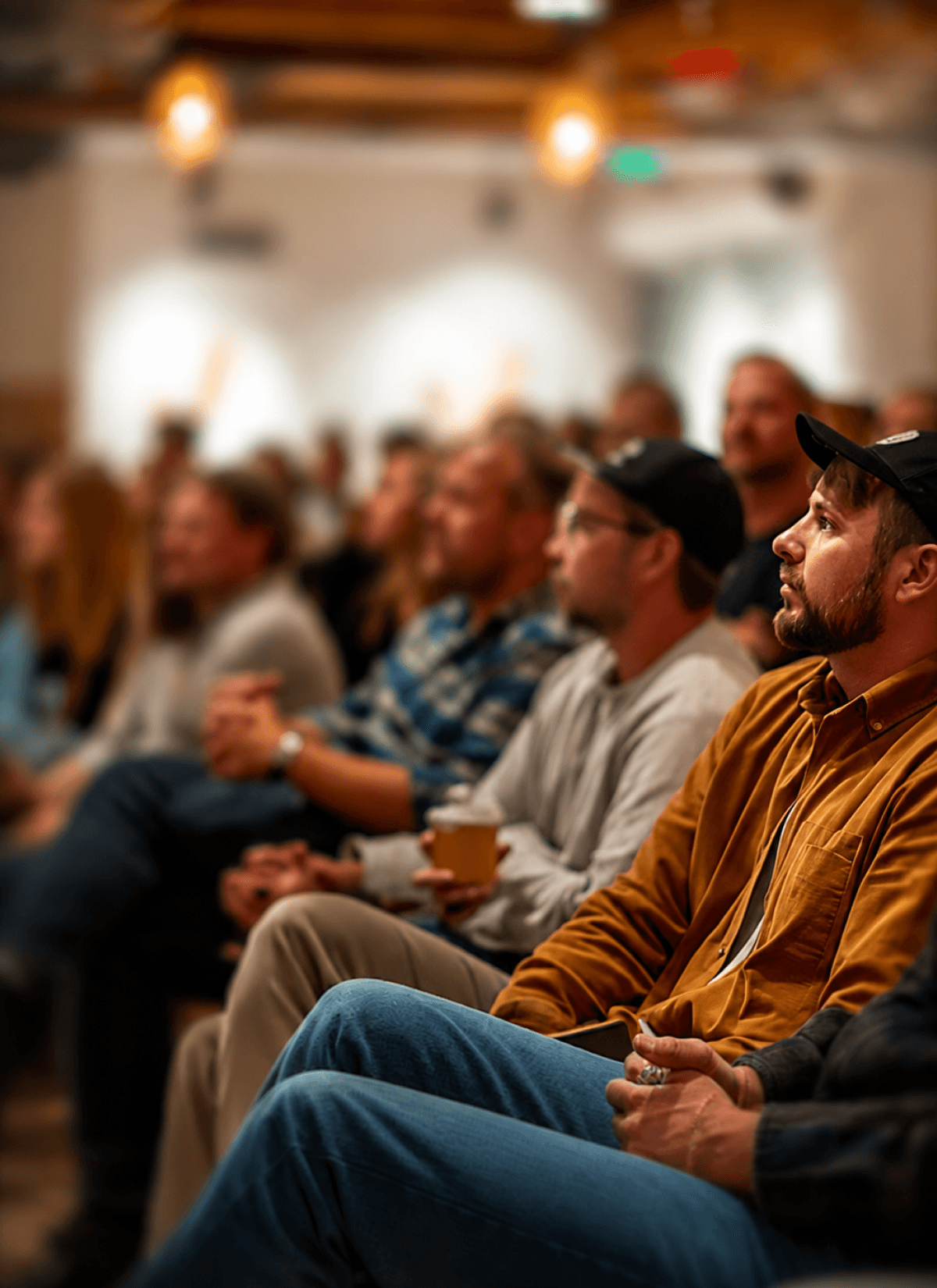 A large, attentive audience filling an event space, with rows of people extending into the background to represent a growing community and subscriber base.